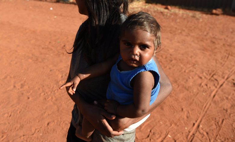 A young mother walks with her child at the Mutitjulu aboriginal community, at the foot of Uluru, also known as Ayres Rock, in the Northern Territory,