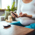 Happy Pregnant woman with glucometer checking blood sugar level at home. Woman testing for high blood sugar. Pregnant Woman holding device for measuring blood sugar