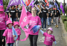 A woman and children participate in a rally for better pay for nurses.