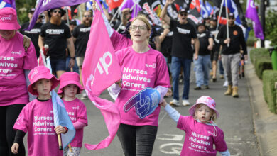 A woman and children participate in a rally for better pay for nurses.