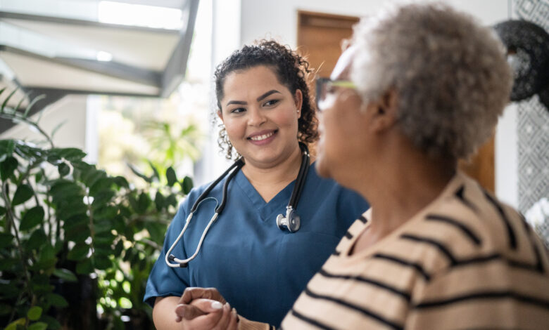 Home caregiver helping senior woman walking at home