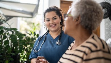 Home caregiver helping senior woman walking at home