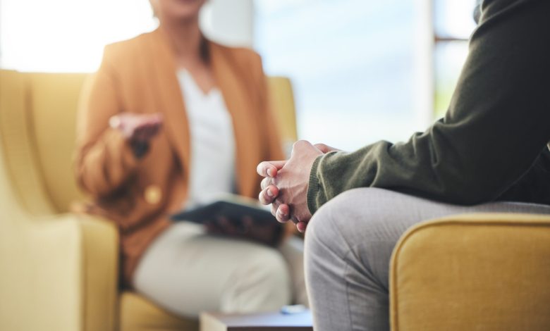 Man, hands and listening for therapy, sofa or advice from woman for mental health, psychology or care. Psychiatrist, patient and frustrated in clinic, session or couch for help, anxiety or depression