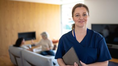 Portrait of nurse with a stethoscope at the patient's home. The Nurse looks at the camera