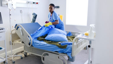 Female cleaner changing bed sheets at the hospital room