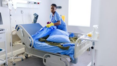 Female cleaner changing bed sheets at the hospital room