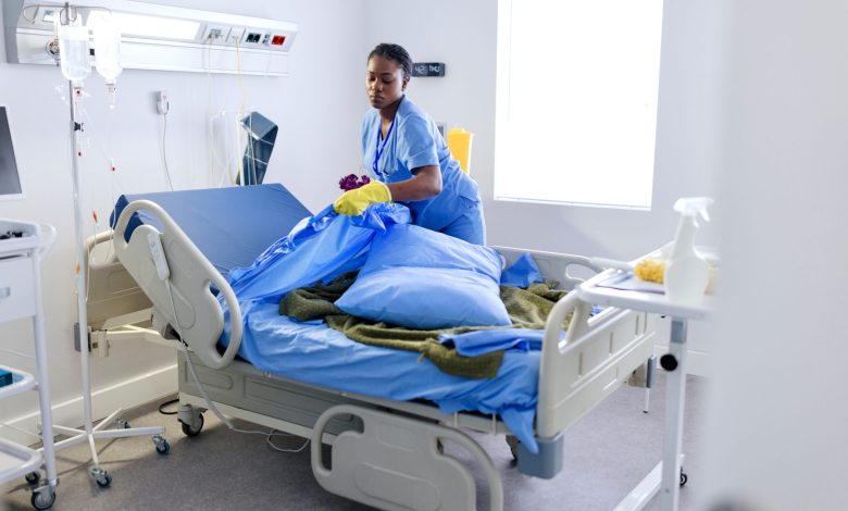 Female cleaner changing bed sheets at the hospital room