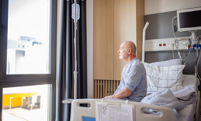 In a hospital setting, an elderly man sits up in his bed, looking out the window. The room is well-equipped with medical devices and provides a sense of comfort during his recovery.