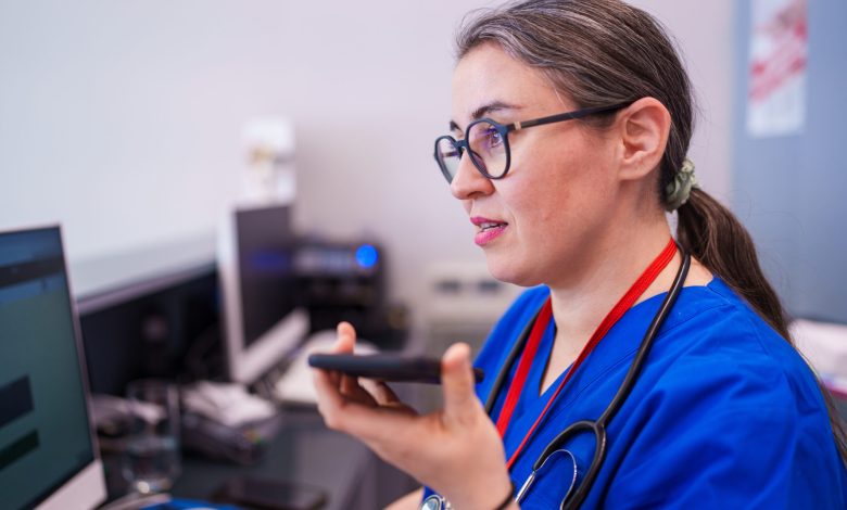 A healthcare worker sits at a desk, focused on using their phone. The scene captures the daily administrative tasks and communication that healthcare professionals manage in a medical setting.
