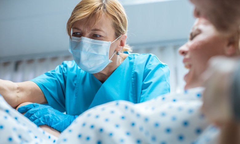 In the Hospital Close-up Shot of Professional Midwives work Assisted by Obstetricians. In Modern Delivery Woman Pushes to Give Birth