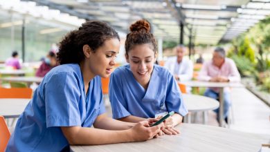 Nurses taking a break from work at the hospital and looking at social media on a cell phone at the cafeteria