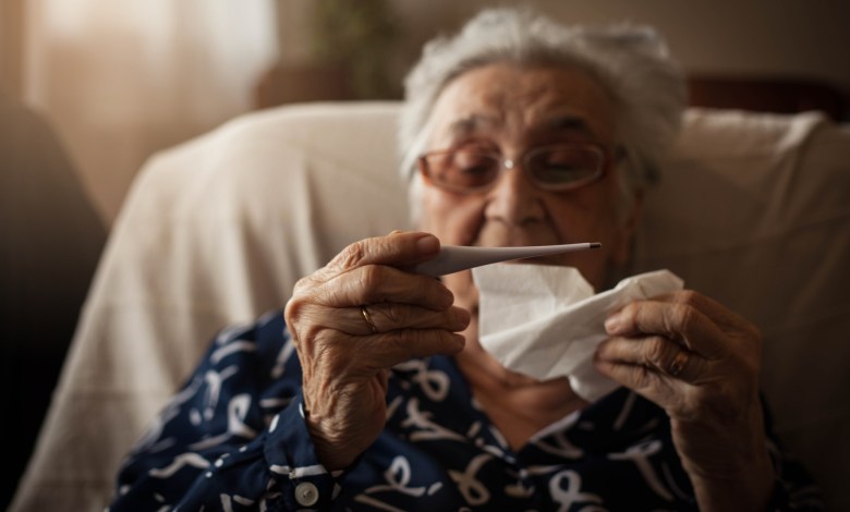 Senior woman holding thermometer ,looking at it.