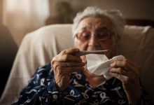 Senior woman holding thermometer ,looking at it.