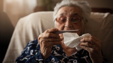 Senior woman holding thermometer ,looking at it.