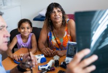 Young Aboriginal girl and her Grandmother consult with their Pacific Islander doctor about her ultrasound results in his office