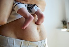 Post partum mother body while holding newborn baby.