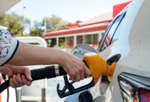 A close up shot of an unrecognisable woman using a fuel pump and filling up a vehicle.
