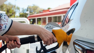 A close up shot of an unrecognisable woman using a fuel pump and filling up a vehicle.