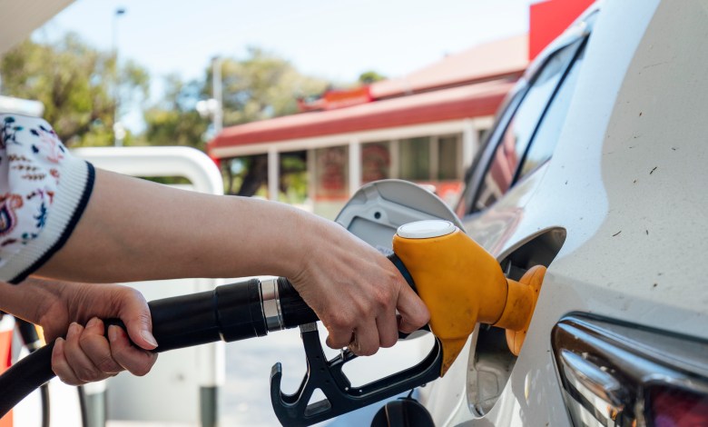 A close up shot of an unrecognisable woman using a fuel pump and filling up a vehicle.