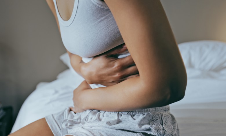 Menstruation, sick and stomach ache with black woman in bedroom for indigestion, cramps and illness. Frustrated, gas and stress with girl on bed for constipation, bloating and intestine problems