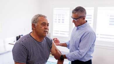 Senior Aboriginal Australian man receiving flu shot from his doctor