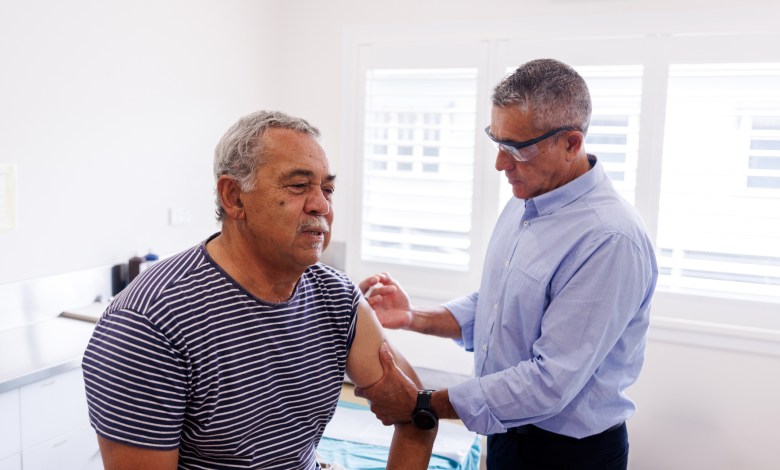 Senior Aboriginal Australian man receiving flu shot from his doctor