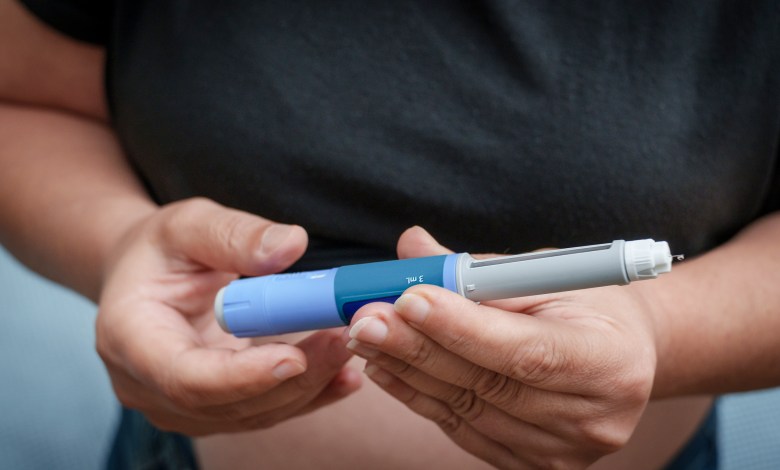 Person's hands holding an insulin pen for diabetes treatment