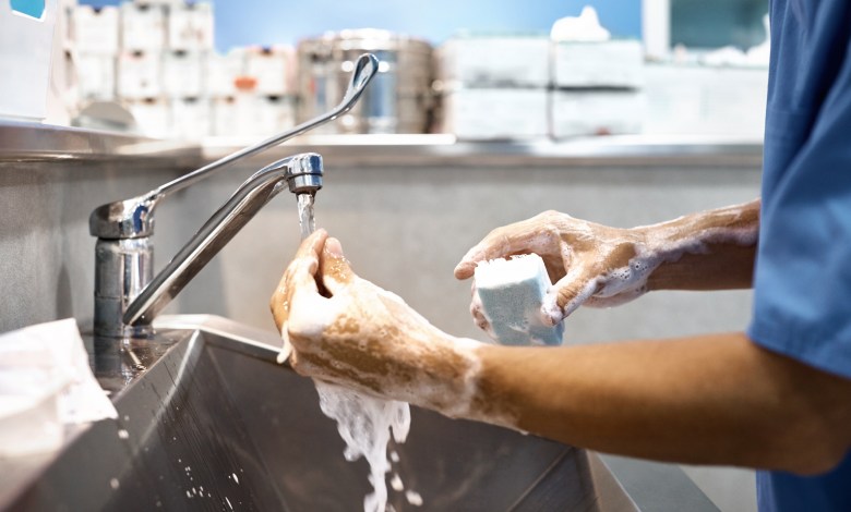 Cropped image of veterinarian washing hands with soap at sink. Close-up of surgeon preparing for surgery. He is in operating room.